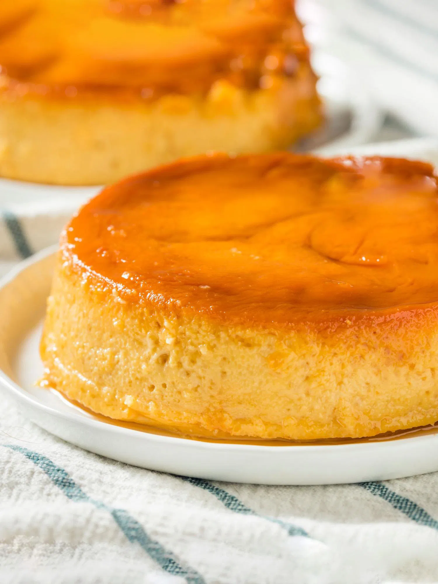 Close-up of a golden homemade flan with glossy caramel topping on a white plate
