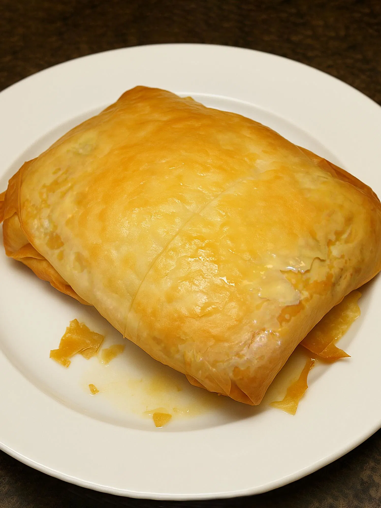 Golden-brown rectangular pastry with flaky layers on a white plate